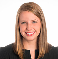 Professional headshot of a woman with long, straight hair, smiling in a black blouse.