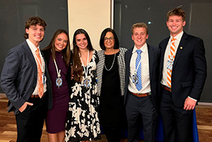 Two males and three females in dress clothing standing beside one another.