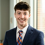 Smiling person in a suit and striped tie in an indoor setting.
