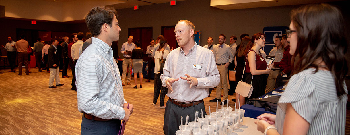 Male students talking at an event.