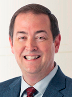 Headshot of a smiling man in a suit with a tie, suitable for a professional profile.