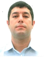 A professional portrait of a man with dark hair, wearing a light blue shirt.