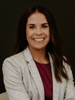 Professional headshot of a woman smiling, wearing a gray blazer over a maroon top.