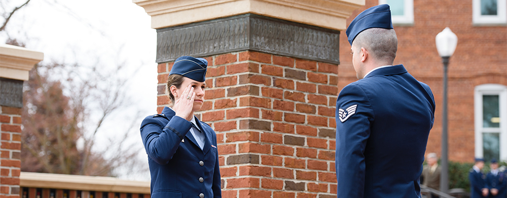 Man and woman in Air Force dress uniforms facing each other and saluting one another.