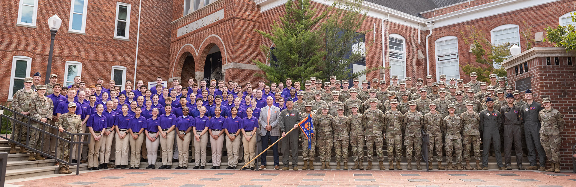 Group photo of male and female students in Air Force camouflage and uniforms standing in front of Tillman Hall.