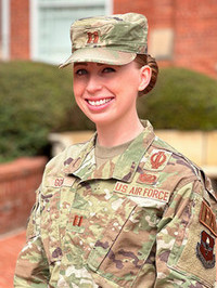 Female U.S. Air Force service member smiling in military uniform with a camouflage pattern.