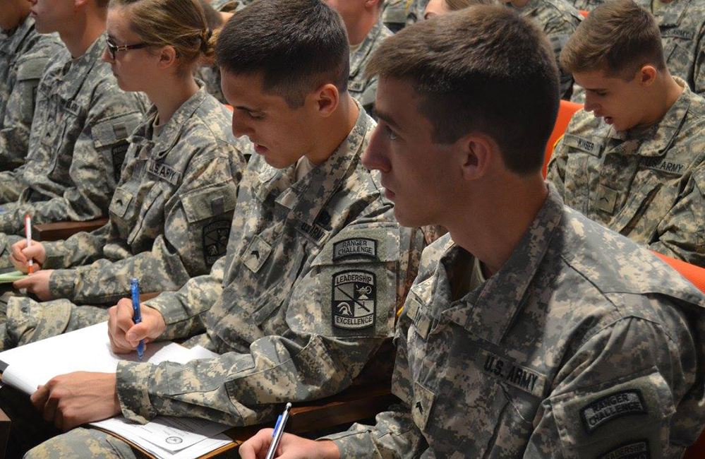 Cadets in camouflage standing outside in group.