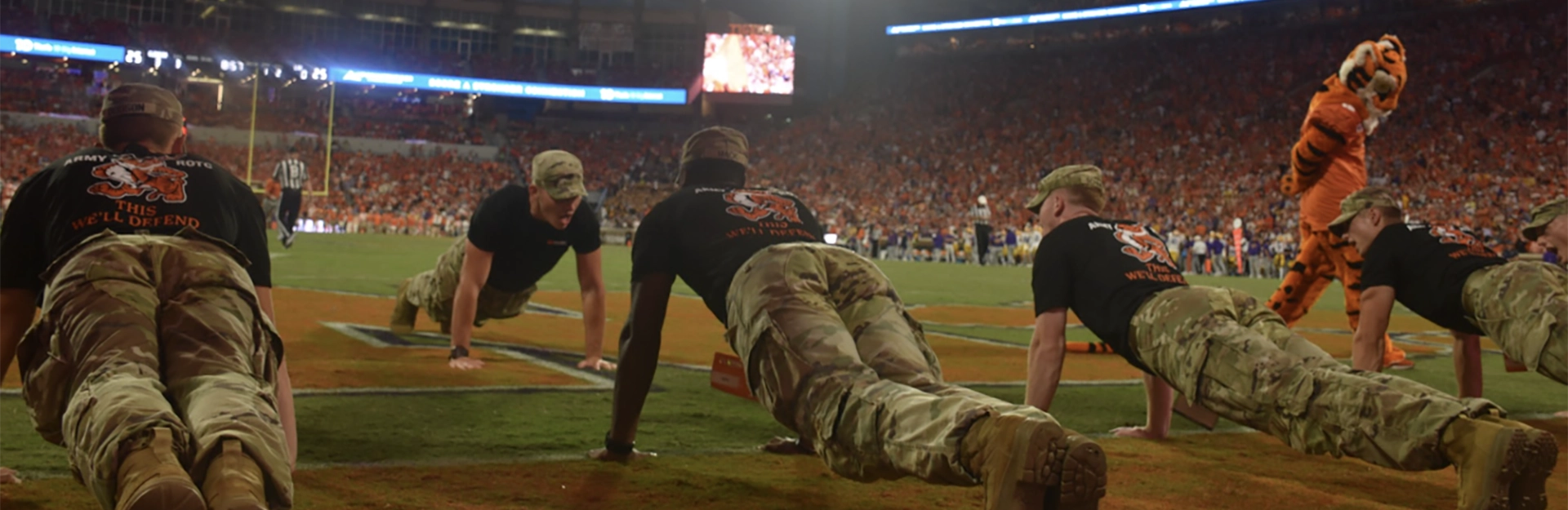 Cadets in camouflage standing outside in group.