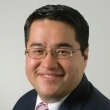 Professional headshot of a smiling man in a suit and tie.