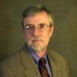 Professional headshot of a mature man with glasses, wearing a suit and tie.