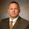 Professional headshot of a man in a suit with a neutral background.