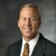 Professional headshot of a man in a suit with a confident smile.