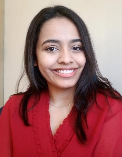 A smiling woman with long dark hair wearing a red blouse.