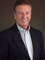 Professional headshot of a smiling man in a dark blazer and light blue shirt.