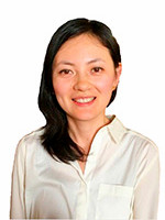 A smiling woman with long dark hair wearing a white blouse against a plain background.