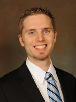 Professional headshot of a smiling man in a suit and tie.