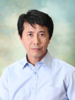 Professional headshot of a man with black hair, wearing a light blue button-up shirt against a soft, textured background.