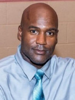 Professional headshot of a man in a gray shirt and teal tie.