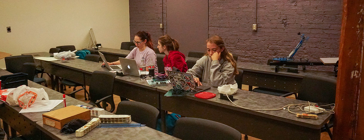 Three females sitting side by side working on laptops.