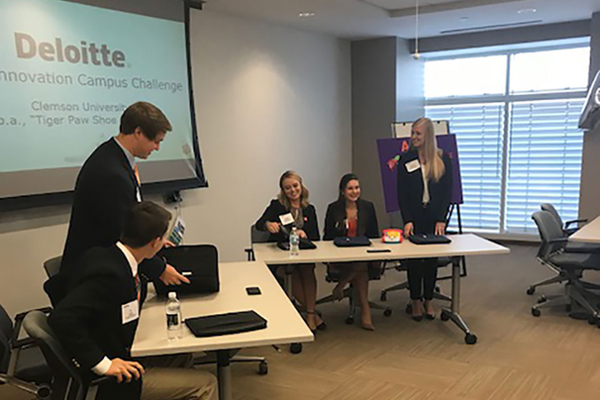 Two male and three females students presenting a PowerPoint presentation.