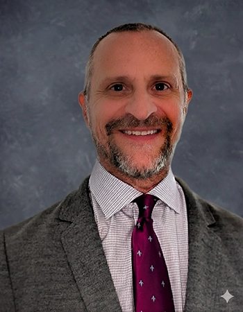 Professional headshot of a man in a gray suit and purple tie against a neutral background.