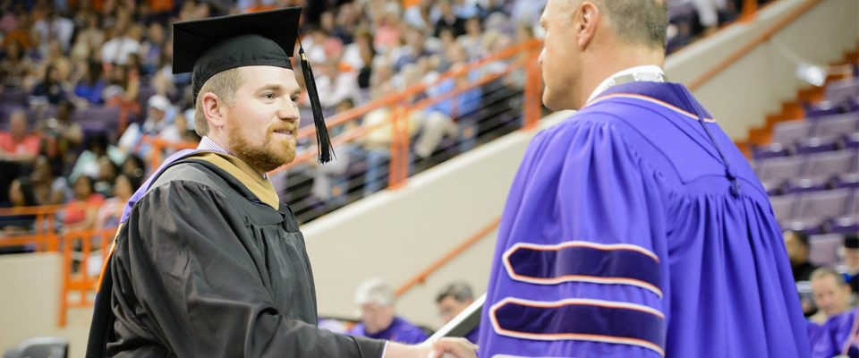 Graduating male student shaking hands with male President Clements.