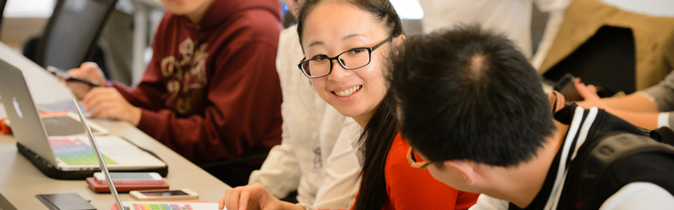 Female with daerk hair and glasses with laptop sitting beside male student with dark hair and glasses. 