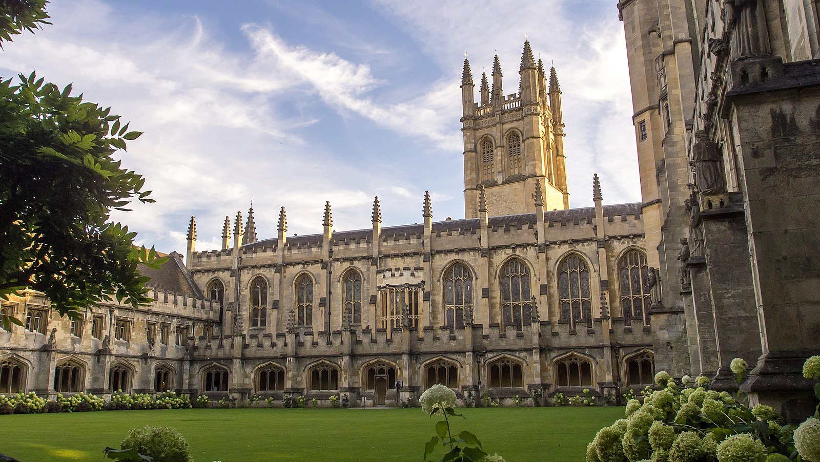 Oxford University with large green lawn and fountain in front.