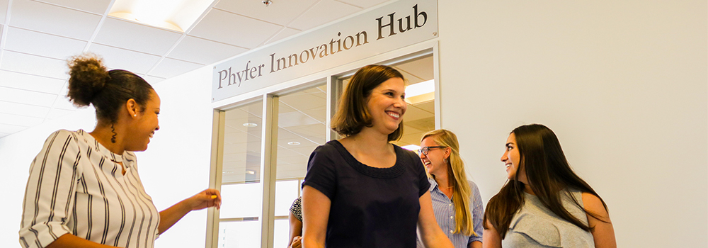 Five females walking and talking in front of the Phyfer Innovation Hub sign.