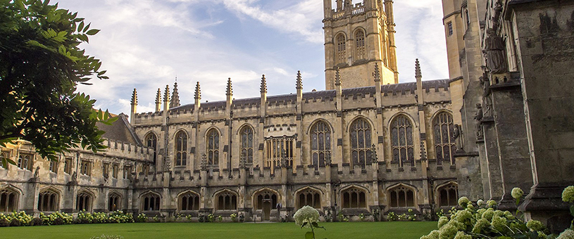 Large building on Oxford Campus with trees and green lawn.