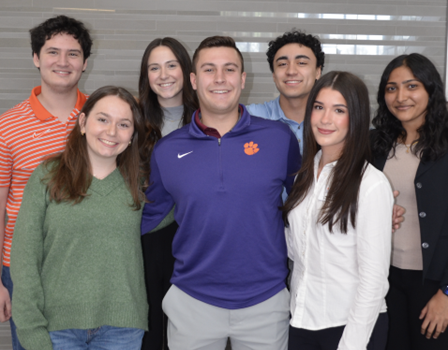 Group of seven students smiling for a photo, showcasing diversity and camaraderie.