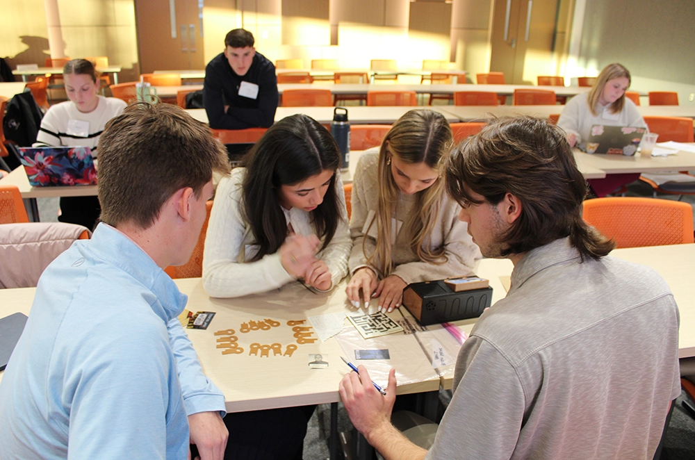 Students collaborate at a classroom table, assembling small parts for a hands-on project.
