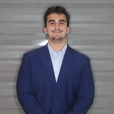 Professional headshot of a man in a blue suit with a confident smile.