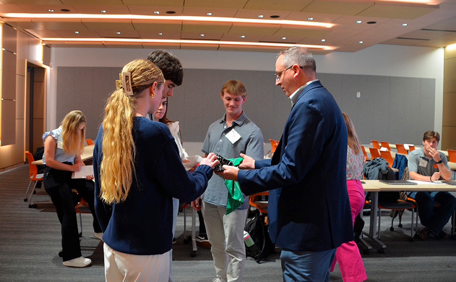 A group of students engaging in a discussion with an instructor in a modern classroom setting.