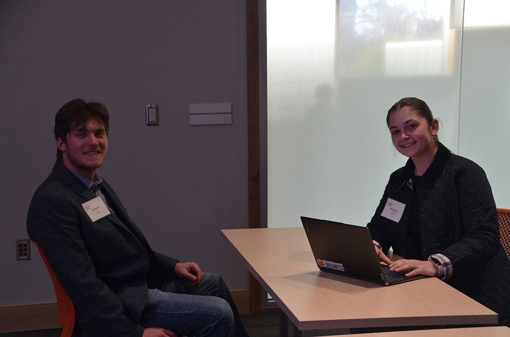 Young professionals engaged in a discussion at a table, one using a laptop.