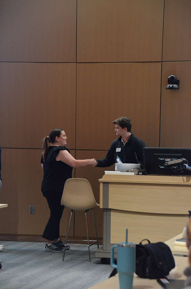 Two individuals shaking hands in a classroom setting.