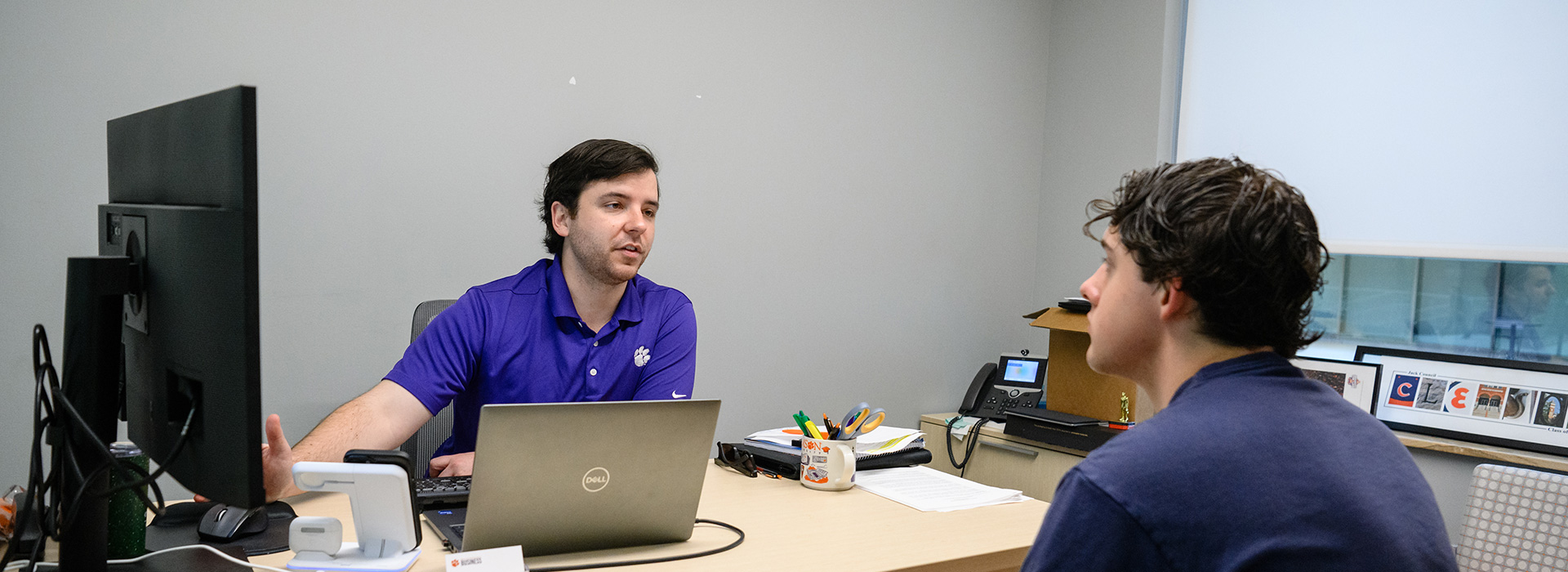 two males with short dark hair sitting across from each other