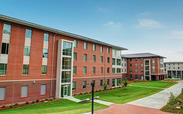 Modern college dormitory building with landscaped green space and walkways.