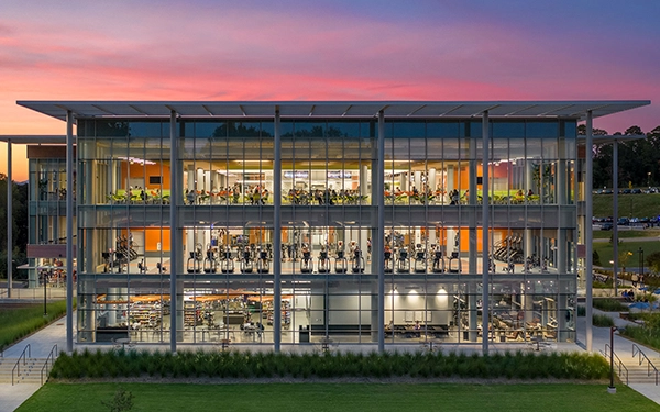 Modern fitness center with large glass windows showcasing workout equipment and a vibrant interior.