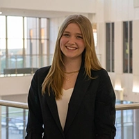 Young woman smiling in a professional setting, wearing a black blazer.
