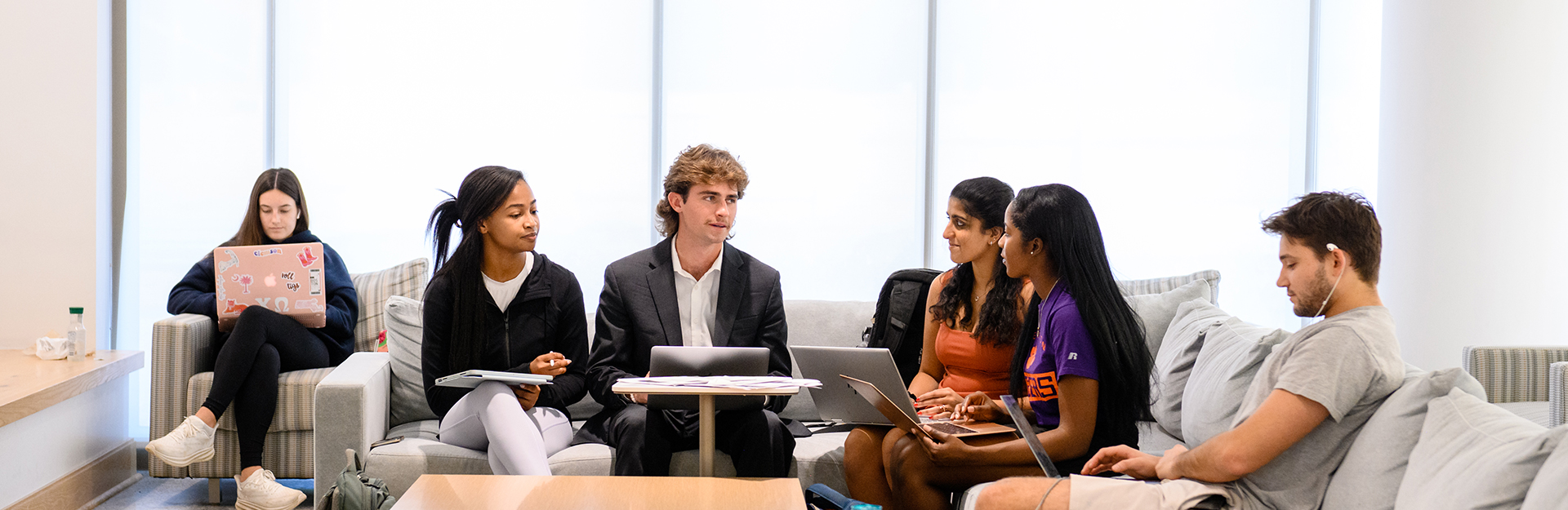 Students sitting in business building on couches.