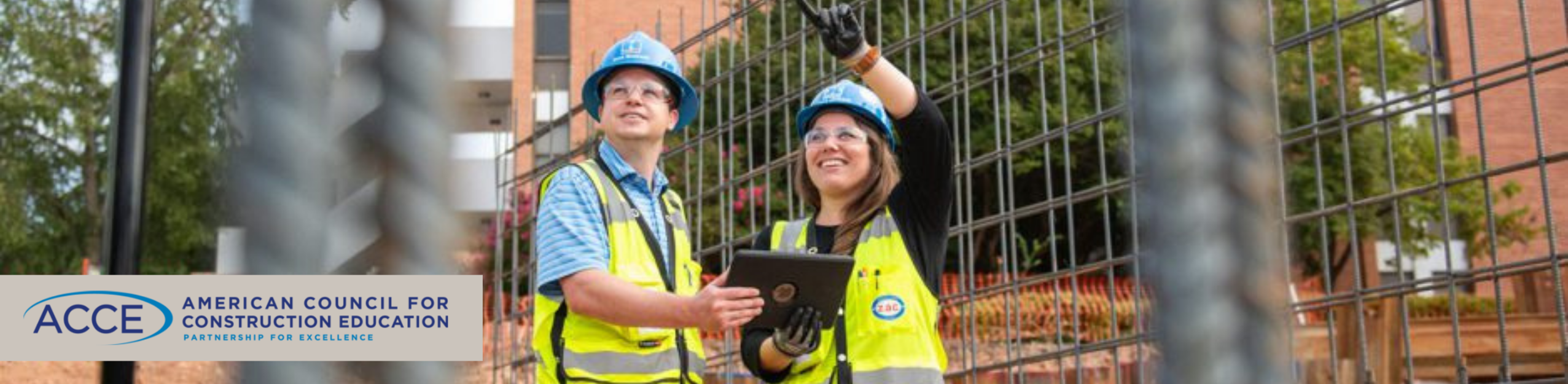 male and female construction worker looking at a construction site looking at  up at their work