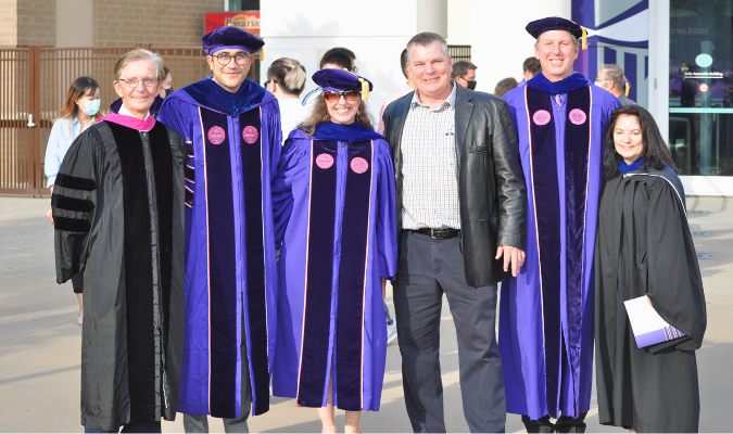 Three graduate students with CSM professors at graduation 