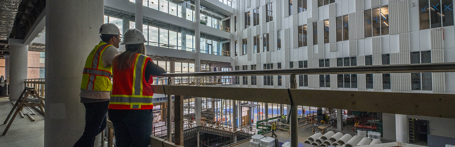 Image of two people wearing hard hats and vests at a construction site