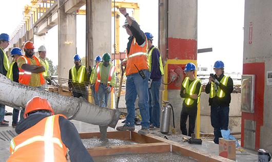 students in hard hats and reflective vests on construction site