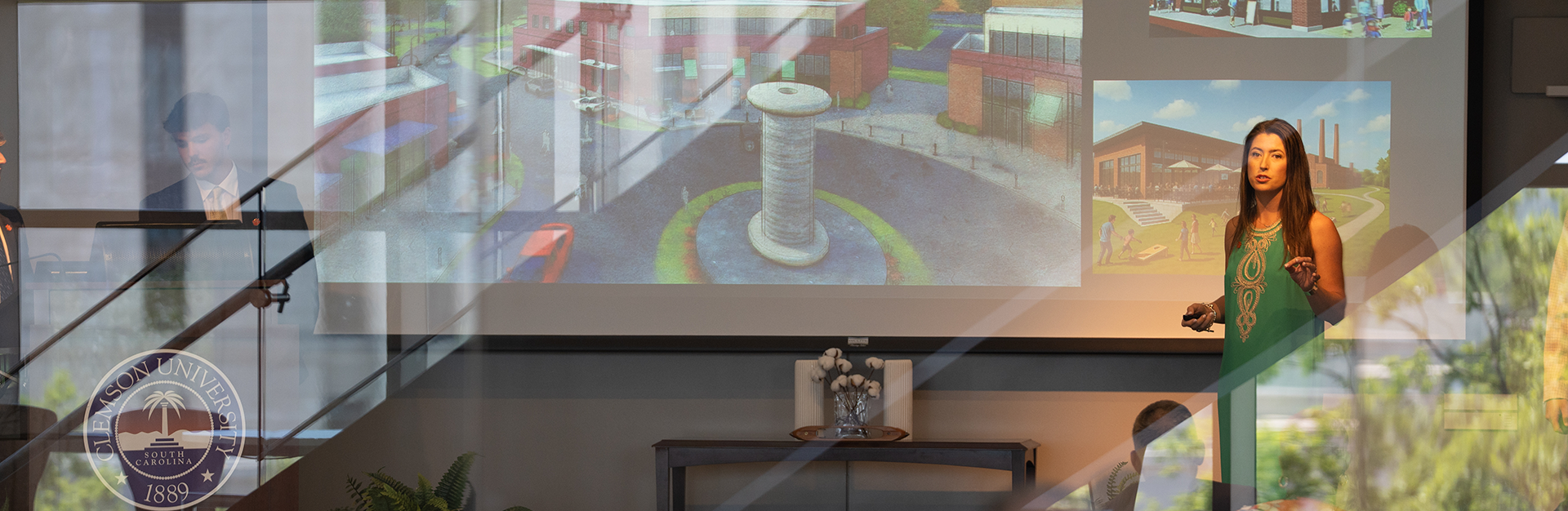 A student delivers a powerpoint presentation in a classroom with large reflective windows