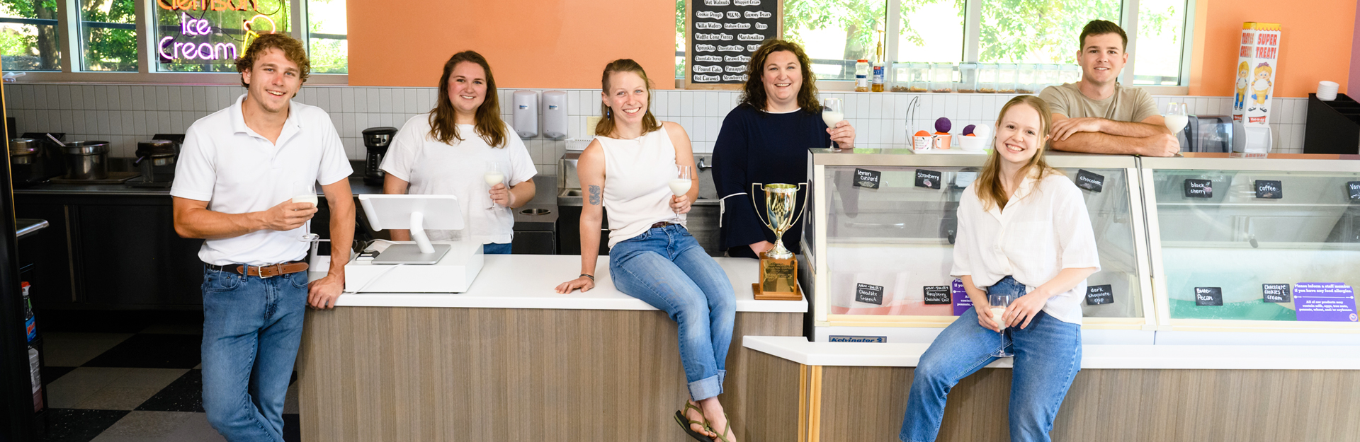 group photo of students sitting on the ice cream counter of clemson's 55 exchange ice cream shop