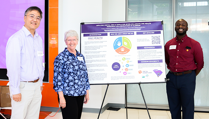 Three presenters standing by their poster