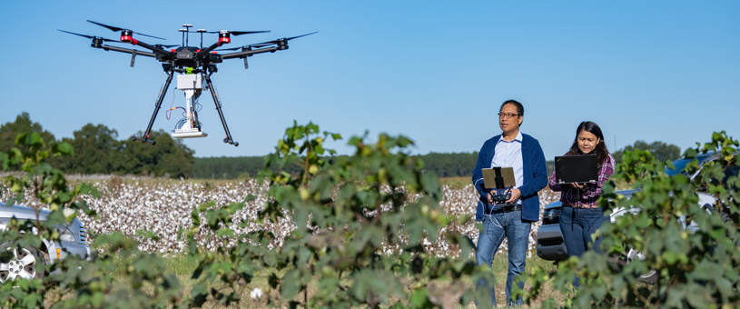 joe mari maja and fellow researcher using a drone to survey agriculture crops