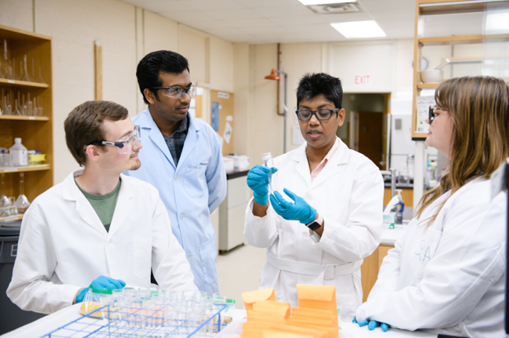 professor Dill working in a lab with gradate stdents